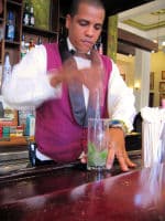 A well dressed bartender mixes up another Mojito.